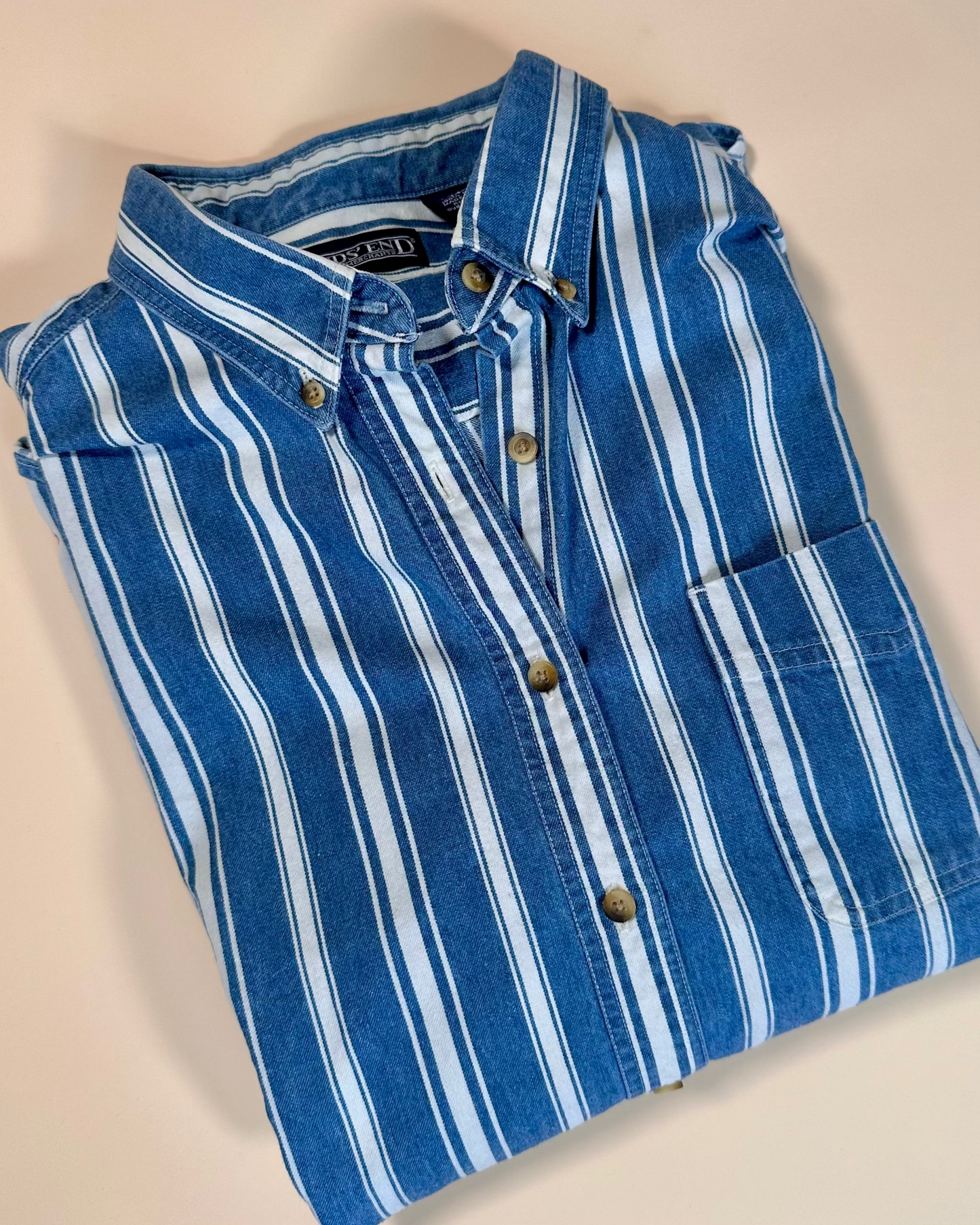 Folded blue and white striped shirt on a beige background