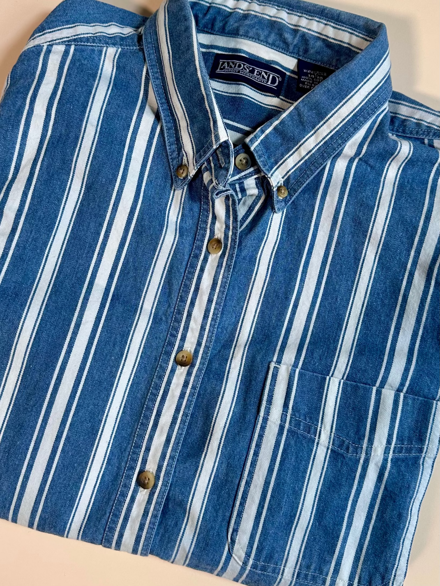 Blue and white striped shirt with a brand label on a beige background