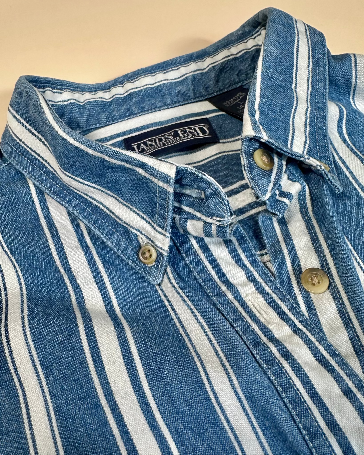 Close-up of a blue and white striped shirt with a brand label on a beige background