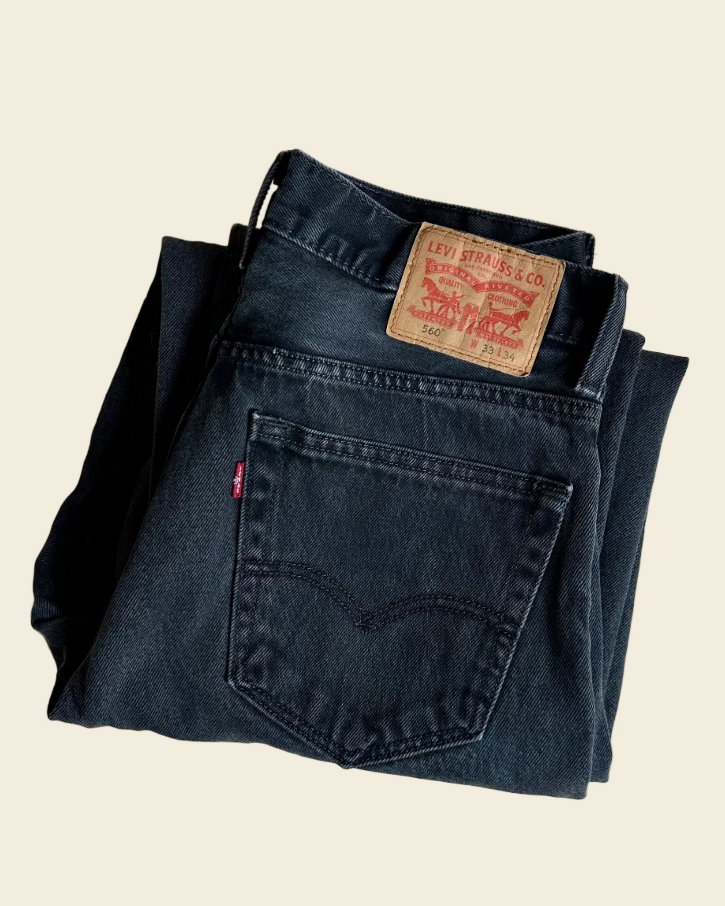 Folded pair of Levi's jeans with a visible label on a beige background
