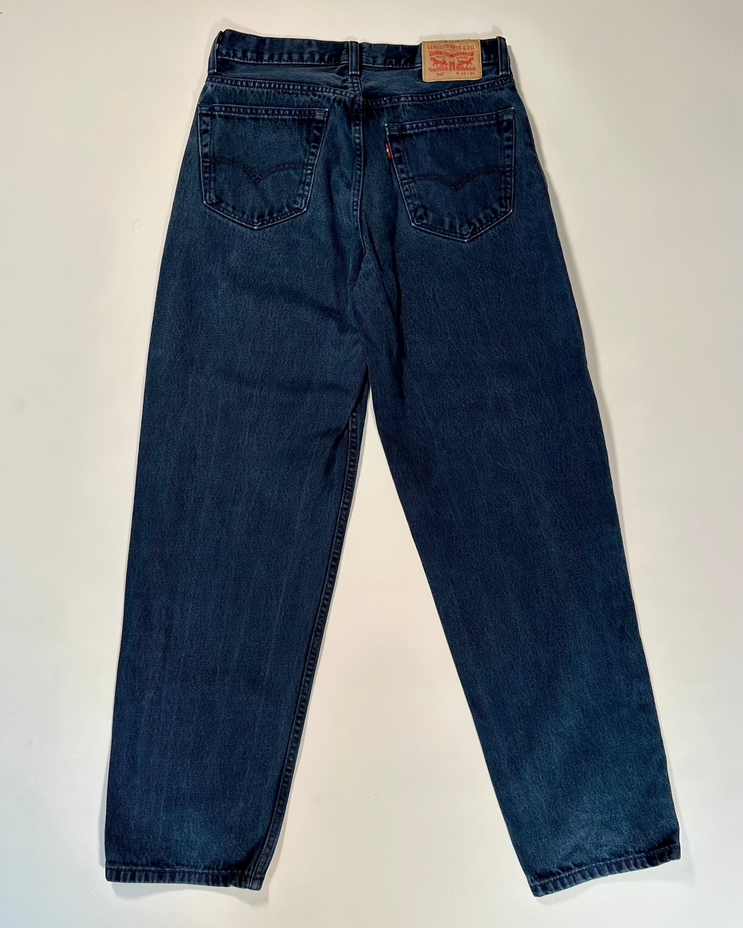 Pair of black jeans with a brand label on a white background